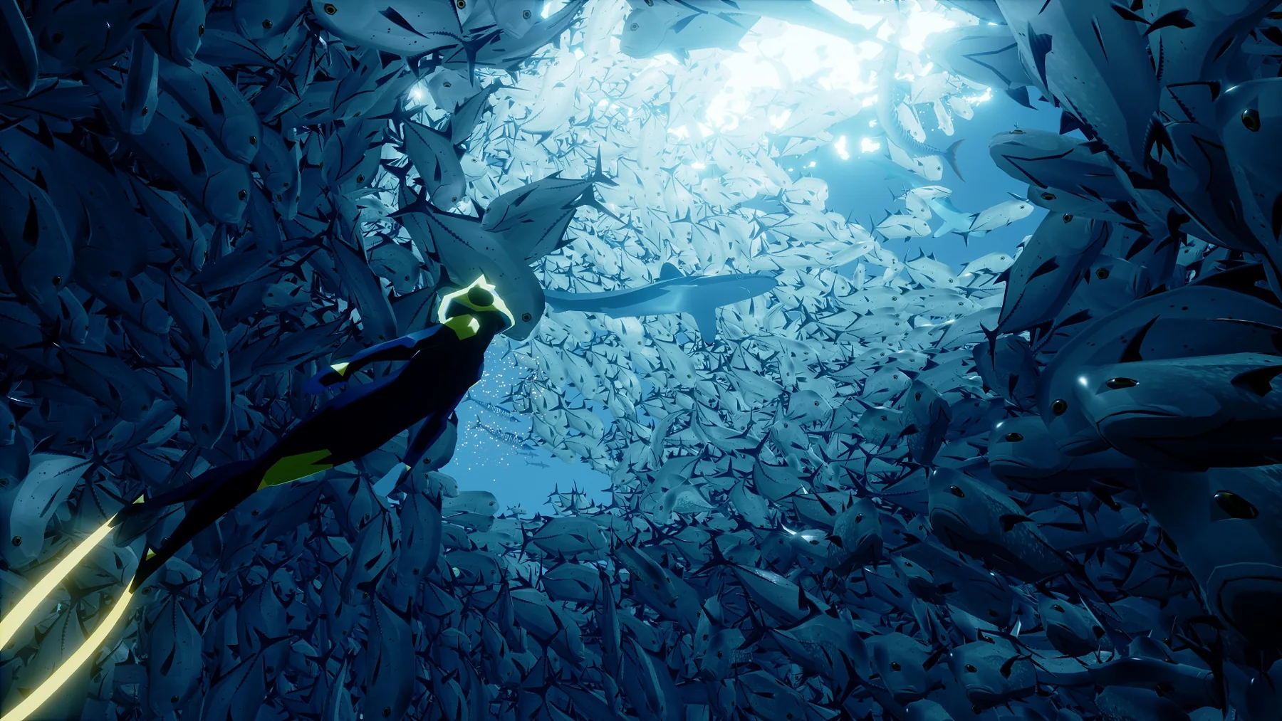 A diver swims beneath a shaft of sunlight through a dense school of fish in ABZU.